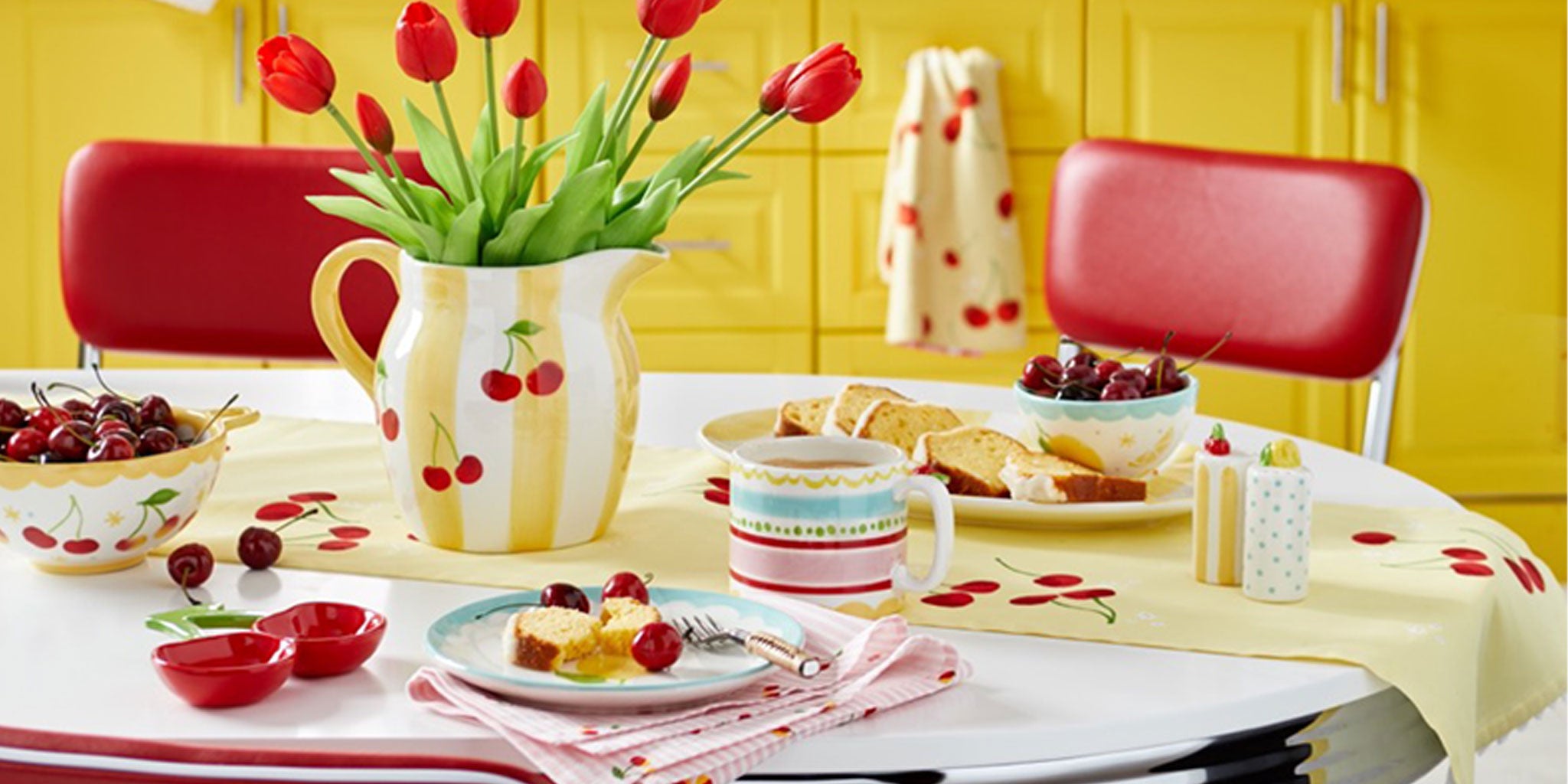 Dining table set with red tulips, fruit, and a yellow wall in the background